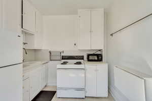 Unit 5 - Kitchen with white cabinetry, light countertops, a sink, and white appliances