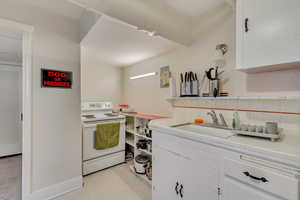 Unit 1 - Kitchen with a sink, open shelves, white electric range oven, tile countertops, and white cabinets