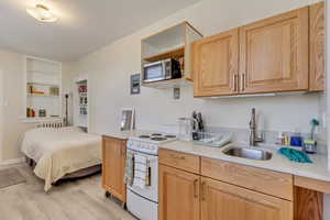 Unit 7 - Kitchen with light countertops, a sink, white electric range, stainless steel microwave, and light wood-style floors