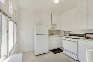 Unit 5 - Kitchen featuring light countertops, white appliances, baseboards, white cabinetry, and a sink