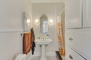 Unit 7 - Bathroom featuring tile patterned flooring, curtained shower, and baseboards
