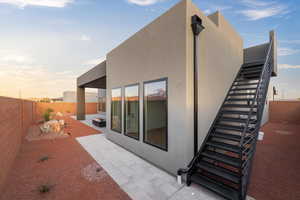 Rear view of property featuring stucco siding, a patio area, a fenced backyard, and stairway