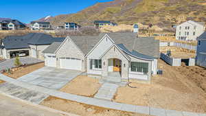 View of front facade with stone siding, concrete driveway, an attached garage, a shingled roof, and central AC unit