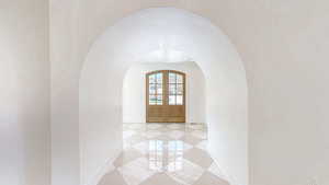 Interior space featuring marble finish floor, baseboards, arched walkways, and french doors
