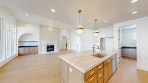 Kitchen featuring built in shelves, a textured ceiling, hanging light fixtures, a sink, and light wood-style flooring