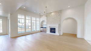 Unfurnished living room with a textured ceiling, a fireplace, baseboards, and light wood-style floors