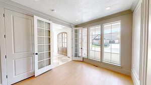 Interior space featuring a textured ceiling, a wealth of natural light, light wood-style flooring, and french doors