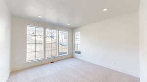 Empty room with a textured ceiling, visible vents, baseboards, recessed lighting, and light carpet