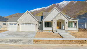 View of front of property featuring stone siding, a porch, driveway, and an attached garage