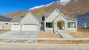 French country style house with stone siding, roof with shingles, concrete driveway, a garage, and a mountain view