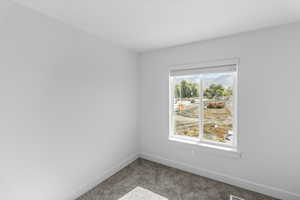 Carpeted spare room featuring baseboards