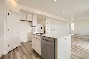 Kitchen with white cabinets, light wood finished floors, dishwasher, recessed lighting, and a sink