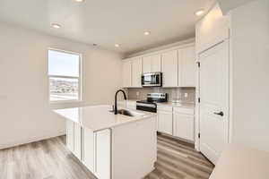 Kitchen with decorative backsplash,  stainless steel appliances, and light wood-type flooring