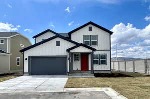 Modern inspired farmhouse with a front yard, board and batten siding, a garage, and concrete driveway