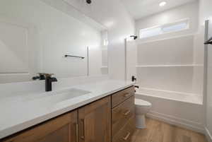 Full bathroom with toilet, bathtub / shower combination, recessed lighting, vanity, and wood finished floors
