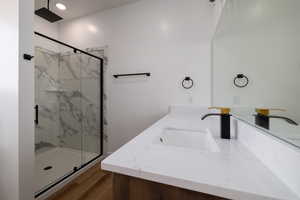 Full bathroom featuring vanity, visible vents, a marble finish shower, and wood finished floors
