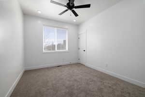 Carpeted empty room with visible vents, baseboards, and a ceiling fan