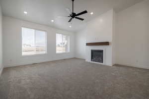 Unfurnished living room featuring recessed lighting, a glass covered fireplace, vaulted ceiling, and carpet floors