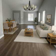 Living area with an inviting chandelier, dark wood-style floors, lofted ceiling, and baseboards