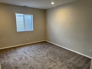 Empty room featuring baseboards, visible vents, recessed lighting, and carpet
