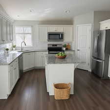 Kitchen featuring a sink, tasteful backsplash, appliances with stainless steel finishes, and dark wood-style flooring (virtual Staging)