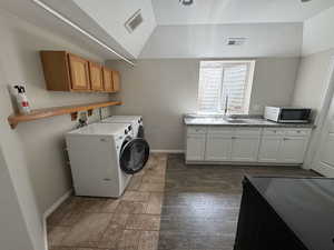 Laundry area featuring visible vents, washing machine and clothes dryer, cabinet space, and a sink