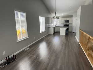 Unfurnished dining area featuring a sink, dark wood finished floors, baseboards, visible vents, and an inviting chandelier