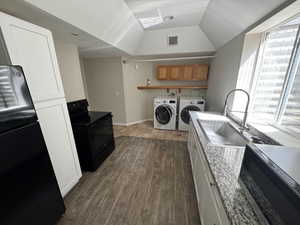 Clothes washing area featuring a sink, wood finished floors, washing machine and clothes dryer, laundry area, and visible vents