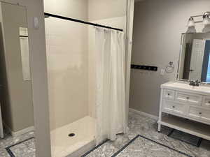 Bathroom featuring baseboards, marble finish floor, a stall shower, and vanity