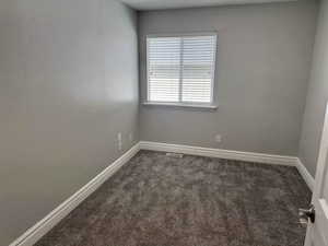 Carpeted spare room featuring baseboards and visible vents
