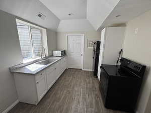 Kitchen featuring dark wood-style floors, visible vents, black appliances, and a sink