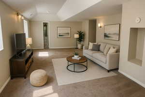 Living room with carpet flooring, baseboards, and vaulted ceiling