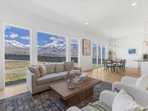 Living area featuring light wood-type flooring, a mountain view, and a healthy amount of sunlight
