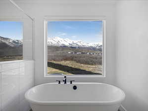 Full bathroom featuring a soaking tub and a mountain view