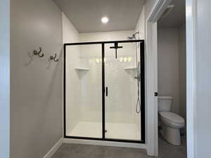 Full bath featuring baseboards, toilet, tile patterned floors, and a shower stall