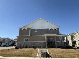 View of front of property with stone siding, a residential view, a front yard, and board and batten siding