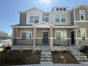 View of front of home featuring stone siding, board and batten siding, stucco siding, cooling unit, and a porch