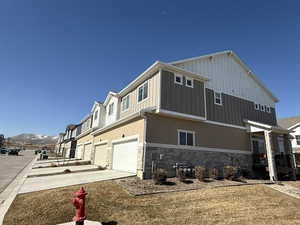 View of home's exterior with stone siding, an attached garage, concrete driveway, stucco siding, and a mountain view