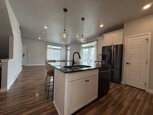 Kitchen with dishwasher, a sink, stainless steel refrigerator with ice dispenser, and dark wood finished floors