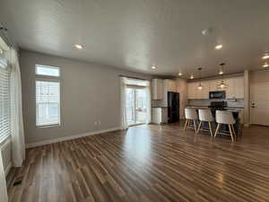 Unfurnished living room featuring dark wood finished floors, baseboards, visible vents, and recessed lighting