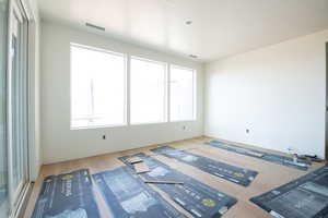 Unfurnished room featuring wood finished floors, visible vents, and a wealth of natural light