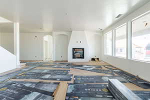 Living room with a fireplace, arched walkways, and a textured ceiling