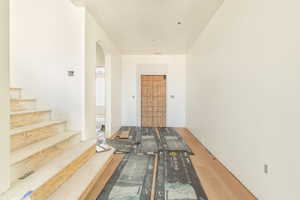 Hall featuring wood finished floors, arched walkways, and stairway