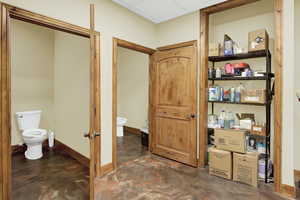 Bathroom featuring a paneled ceiling, baseboards, concrete floors, and toilet