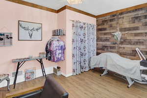 Bedroom with wood finished floors, visible vents, and wooden walls