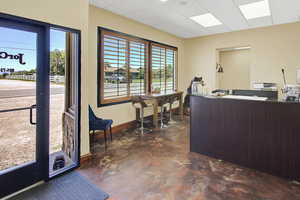 Office area with baseboards, a paneled ceiling, a wealth of natural light, and finished concrete floors