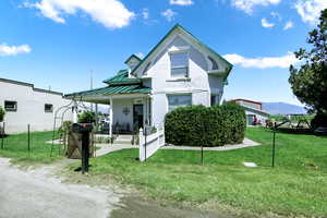 View of front of house featuring metal roof, brick siding, fence, a front lawn, and a standing seam roof