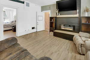 Living area with crown molding, a fireplace, visible vents, and wood finished floors