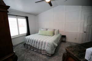 Bedroom with carpet floors, a decorative wall, lofted ceiling, and ceiling fan