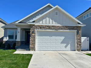 Craftsman inspired home featuring board and batten siding, stone siding, driveway, and an attached garage